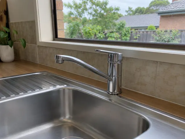Chrome kitchen sink tap over a stainless sink and tiled splashback with timber bench in Frenchs Forest